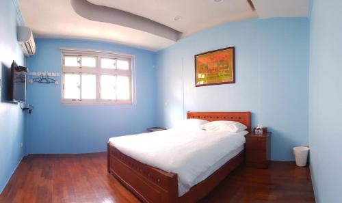 a blue bedroom with a bed and a window at JiuZhiAn Apartment in Wujie