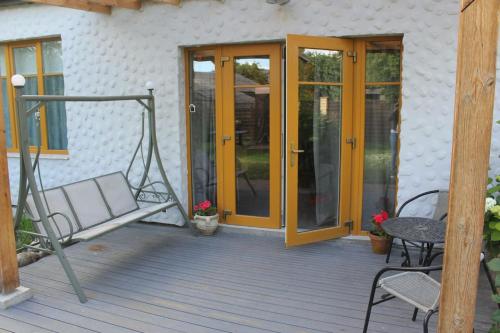 a patio with a swing and a chair on a deck at Sigulda City Center Holiday House in Sigulda