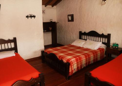 a bedroom with two beds with red sheets at Hostal El Zafiro Del Café in El Mesón