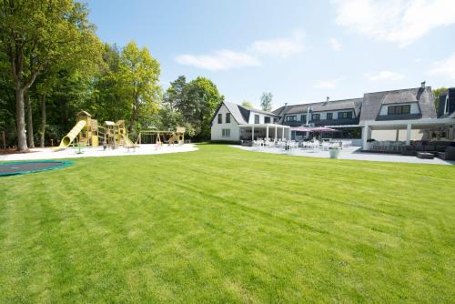 a large yard with a playground and a house at Charmehotel Klokkenhof in Brasschaat