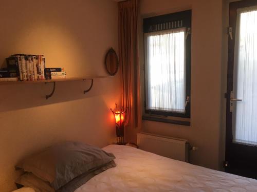 a bedroom with a bed and two windows and a lamp at B&B Looier in Amsterdam