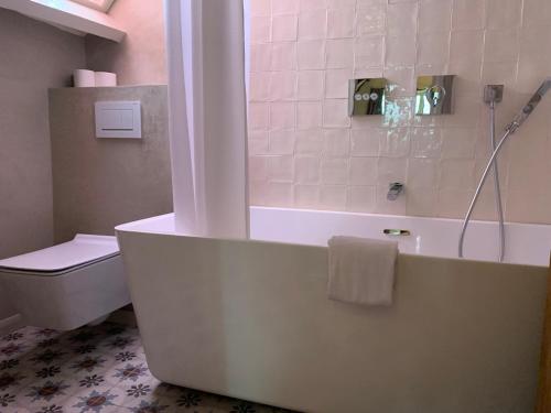 a bathroom with a bath tub and a toilet at Hotel Salvators in Bruges