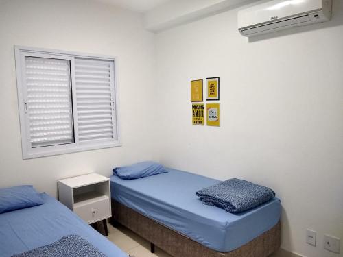 2 camas individuales en una habitación con ventana en Apartamento Villa di Fiore (novissimo), en Guarujá