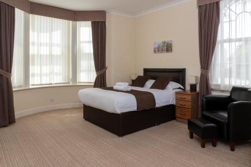 a bedroom with a bed and a chair and windows at The Lawns Guest House in Retford