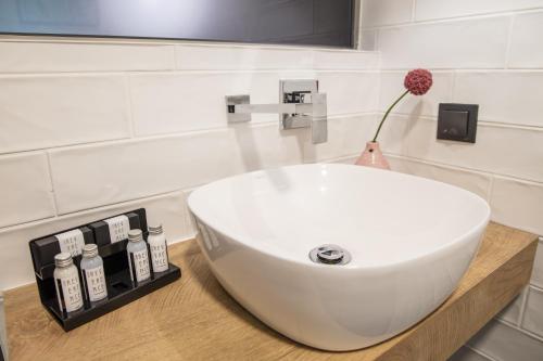 a bathroom with a white sink and a vase with a flower at Reverence Boutique Hotel in Varna City