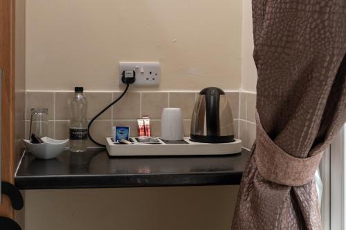 a black counter with a coffee maker and a phone at The Lawns Guest House in Retford