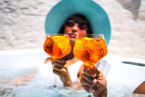 a woman holding up two wine glasses in a pool at Borgo Cozzana in Monopoli