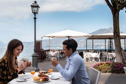 un hombre y una mujer sentados en una mesa con un plato de comida en Benaco36, en Torri del Benaco