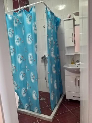 a bathroom with a shower with a blue shower curtain at Sunrise Hotel & Camping in Struga