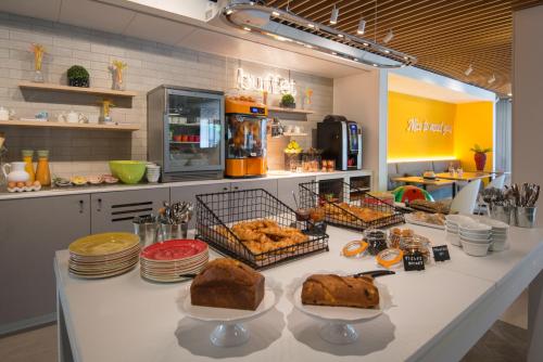 une boulangerie avec une table avec du pain et d'autres aliments dans l'établissement ibis Styles Nice Cap 3000 Aéroport, à Saint-Laurent-du-Var