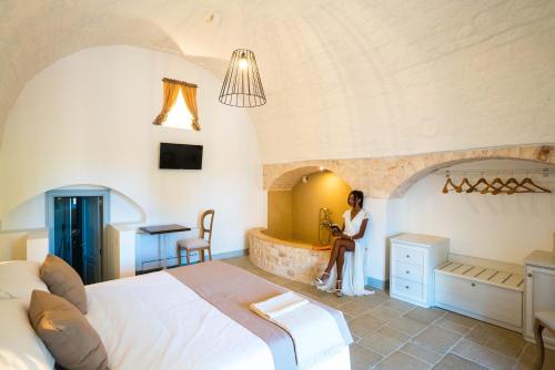 a woman sitting in a hotel room with a bed at Borgo Cozzana in Monopoli