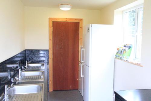 a kitchen with a sink and a refrigerator at Woodbatch Camping & Glamping in Bishops Castle