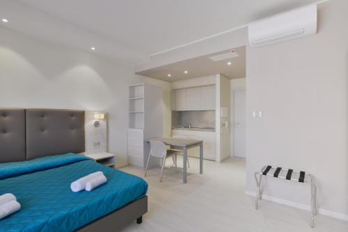 a bedroom with a bed and a table and a kitchen at Residence Picalè in Alghero