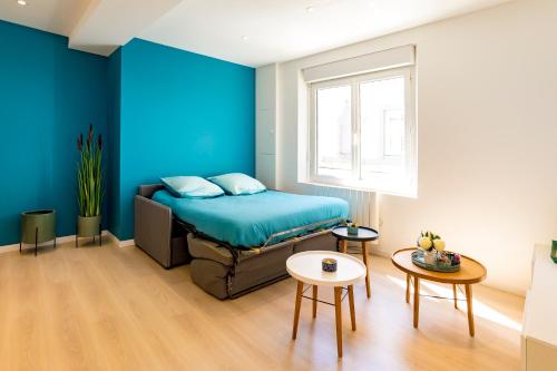 um quarto com paredes azuis, uma cama e uma mesa em Saint-Malo With Love, Parking, Netflix, Wifi em Saint Malo