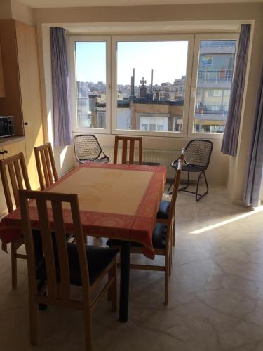una sala da pranzo con tavolo, sedie e una grande finestra di Koksijde-bad de block zeelaan C6 a Koksijde