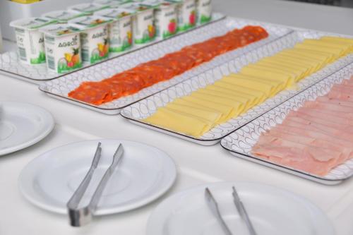 a table with plates and utensils and cheese and meats at Hotel Sol Algarve by Kavia in Faro