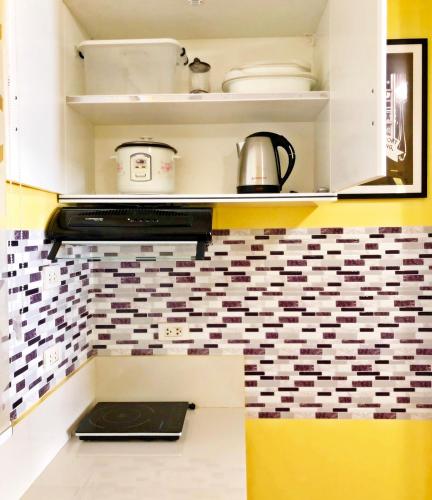 a kitchen with white cabinets and a tile wall at ARC 2219 Home Rentals 2BR in Cebu City