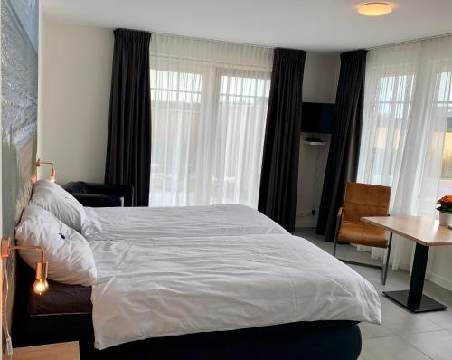 a bedroom with a large white bed and a table at Groede B&B in Groede