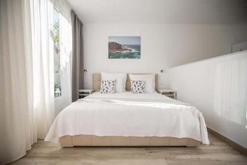 a white bedroom with a large bed and a window at Villa Jandia Luxury Bungalow in Morro del Jable