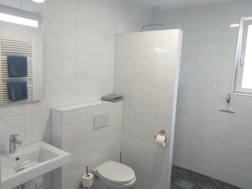 a white bathroom with a toilet and a sink at Groede B&B in Groede