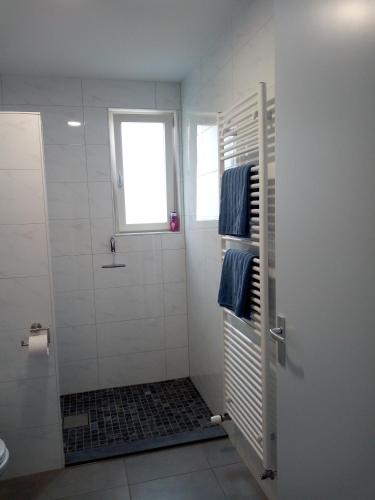 a bathroom with a shower with a window and blue towels at Groede B&B in Groede
