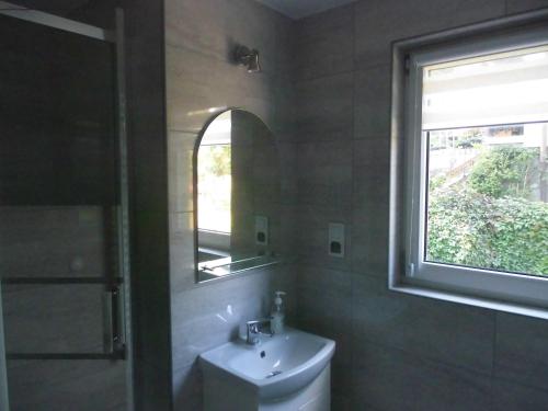 een badkamer met een wastafel, een spiegel en een raam bij Bezowy pokój in Jedlina-Zdrój