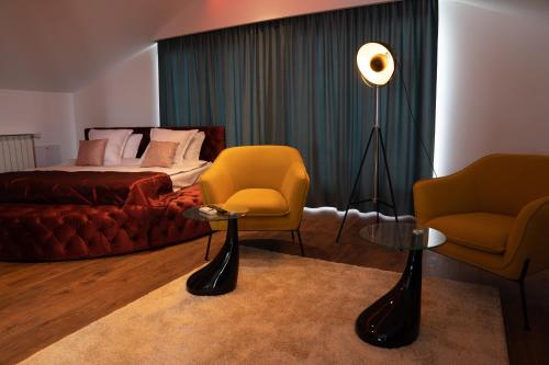 um quarto com uma cama, 2 cadeiras e um candeeiro em The Residence Central Jacuzzi Boutique (Adult Only) em Cluj-Napoca