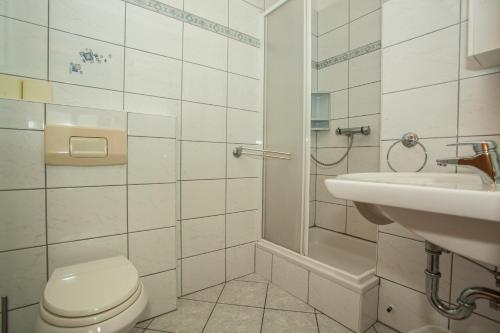 a white bathroom with a toilet and a sink at Apartments Pušić in Omiš