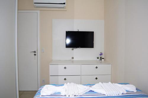 a bedroom with a bed with a tv on the wall at Sun Paradise - JTR in Maceió