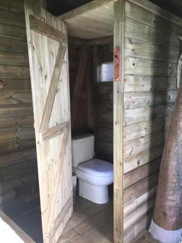 a bathroom with a toilet in a wooden cabin at Ali-Naïs Location in Deshaies