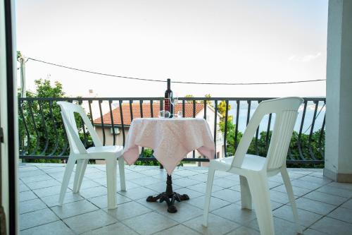 a table and chairs on a balcony with a bottle of wine at Apartments Pušić in Omiš