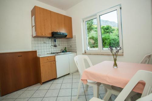 a kitchen with a table and a table and a window at Apartments Pušić in Omiš