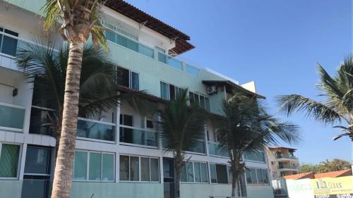 un bâtiment avec des palmiers devant dans l'établissement Apartamento Vista Magnífica frente ao mar, à Luis Correia
