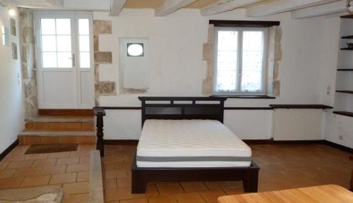 a bed in a room with two windows at l'atelier du relieur in Montmorillon