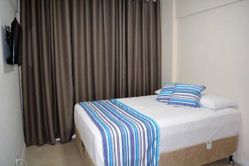 a bed with blue and white pillows in a room at Sun Paradise - JTR in Maceió