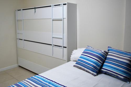 a white bed with two blue and white pillows on it at Sun Paradise - JTR in Maceió