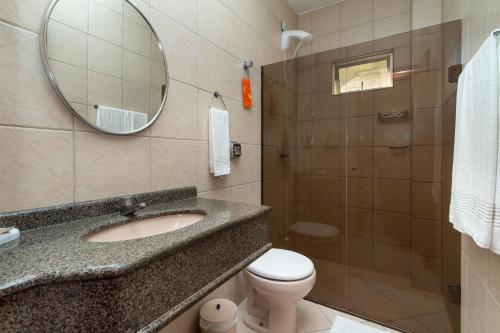 W łazience znajduje się umywalka, toaleta i lustro. w obiekcie Acapulco - Apartamentos em Bombinhas w mieście Bombinhas