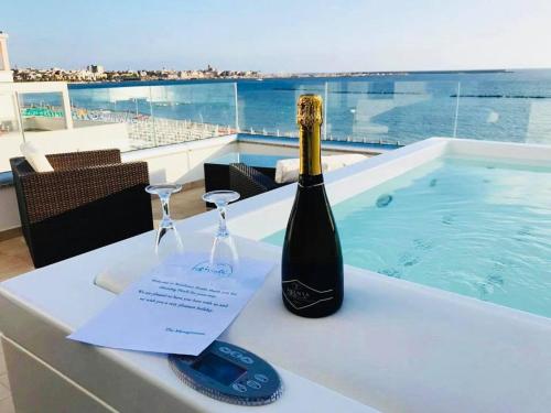 a bottle of champagne and glasses on a table next to a swimming pool at Residence Picalè in Alghero
