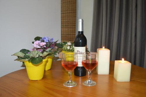 a bottle of wine and two glasses on a table with candles at Sun Paradise - JTR in Maceió