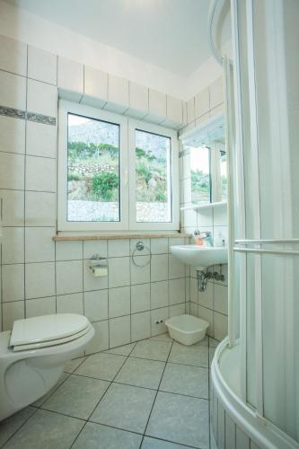 a bathroom with a toilet and a sink and a tub at Apartments Pušić in Omiš