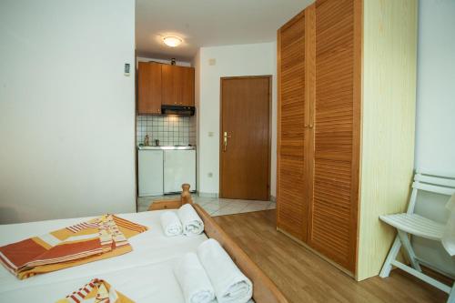 a room with a bed with white sheets and a kitchen at Apartments Pušić in Omiš