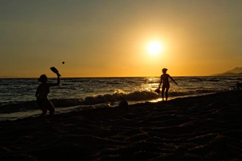 two people playing frisbee on the beach at sunset at Hotel Loukas Vrachos in Paralia Vrachou