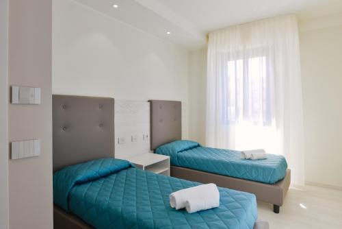 a bedroom with two beds and a window at Residence Picalè in Alghero