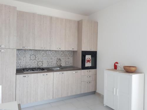 a kitchen with white cabinets and a white refrigerator at AD in Capo dʼOrlando
