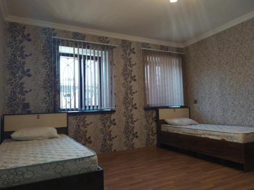 two beds in a room with two windows at VM Hostel in Ganja
