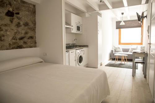 a white room with a bed and a kitchen at LA ATALAYA in Ribadesella