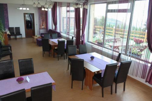 a restaurant with tables and chairs and large windows at Perla Munților in Ranca