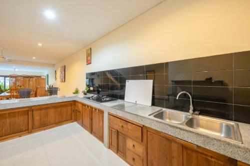 a large kitchen with wooden cabinets and a sink at Mardika Private Villa in Ubud
