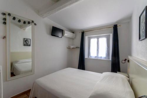 a bedroom with a white bed and a mirror at Hotel Le Flore in Fréjus