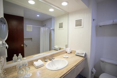 a bathroom with a sink and a mirror and a toilet at Hotel Castillo Huatulco & Beach Club in Santa Cruz Huatulco